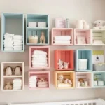 Nichos decorativos de caixote organizados na parede do quarto de bebê com itens essenciais e decorativos